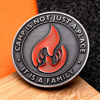 Antiqued nickel challenge coin featuring a red flame emblem and text Camp Is Not Just A Place It Is A Family