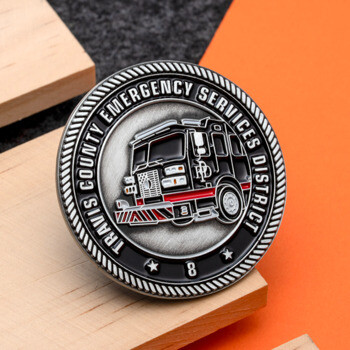 Travis County Emergency Services District challenge coin featuring a black fire engine with red accents and a rope border design.
