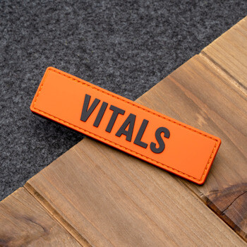 Orange PVC patch with raised black VITALS lettering and matching orange perimeter stitching.