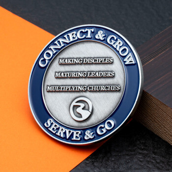 Round silver and blue challenge coin featuring the text Connect & Grow Serve & Go with three mission statements and a small logo.
