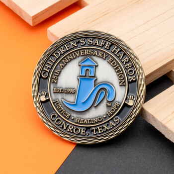 Antique bronze challenge coin for Children's Safe Harbor 25th Anniversary Edition featuring a blue lighthouse logo.