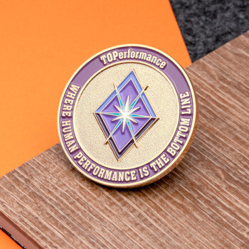 Circular TOPerformance challenge coin with a purple diamond emblem and gold textured background.