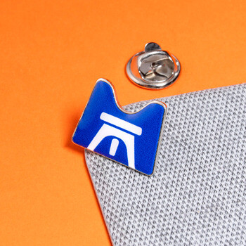 Custom blue and white bridge emblem lapel pin attached to grey fabric with a butterfly clutch back.