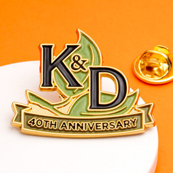 Gold-plated enamel lapel pin celebrating K&D 40th Anniversary with green leaf details and butterfly clutch backing